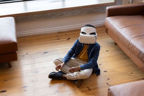 African American Child Exploring Virtual Reality Sitting Cross-Legged on Wooden Floor