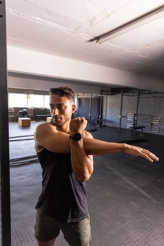 Confident athlete stretching at gym enhancing flexibility