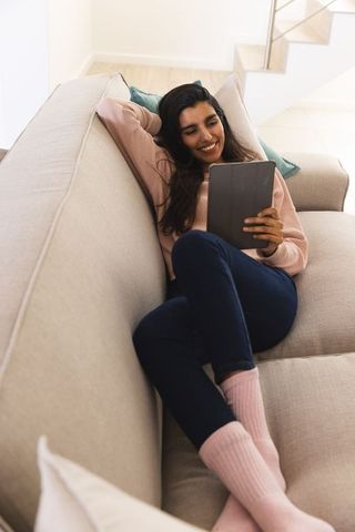 Smiling woman relaxing with tablet on cozy sofa in modern living room