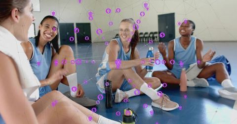 Female basketball players chatting and hydrating on gym court showing team camaraderie
