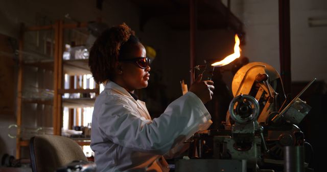 Side view of black female worker blowing glass in glass factory. Black female worker heating glass 4k