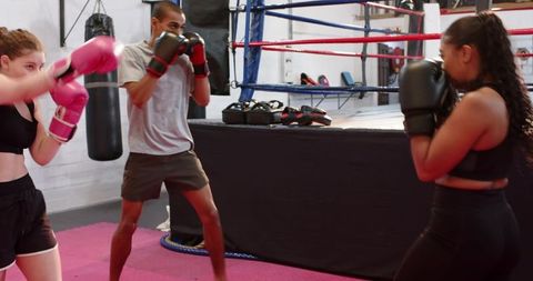 Diverse boxing coach training mixed group practicing jabs, slips and defensive footwork