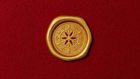 Antique style gold seal medallion resting on deep crimson velvet with rosette cutout detail