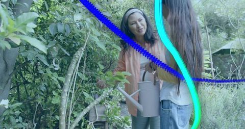 Two women gardening and talking in backyard holding watering can and potted plants
