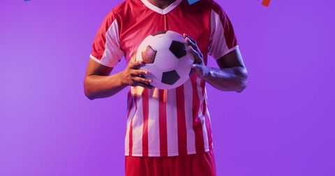 Soccer Player Holding Ball on Purple Background with Copy Space
