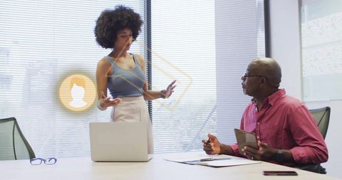 Woman presenting to colleague in modern boardroom with laptop, tablet and ar collaboration