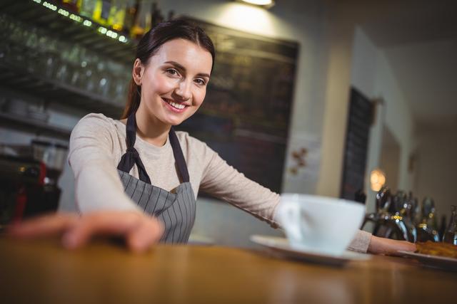 Portrait of smiling waitress standing at counter in cafÃ©