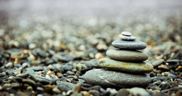 Image showing a stack of smooth pebbles balanced on a rocky beach surface, symbolizing calmness and equilibrium. Perfect for use in wellness blogs, meditation centers, mindfulness workshops, and publications about nature and tranquility.
