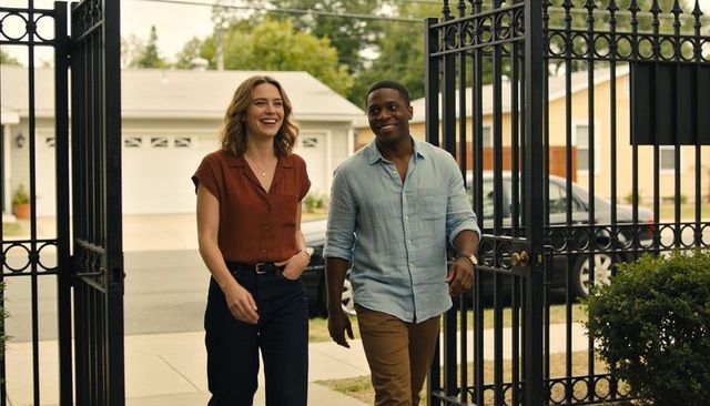 Happy couple walking through iron gate at suburban home front entry smiling and chatting