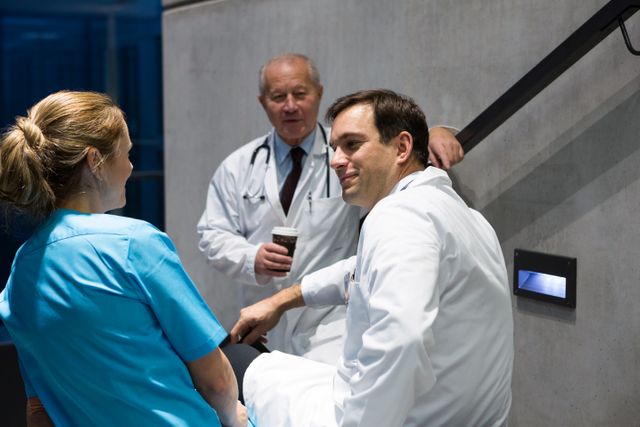 Doctors and surgeons interacting with each other on staircase in hospital