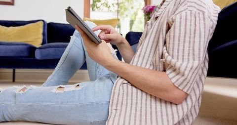 Young Man Relaxing Using Tablet Device in Cozy Living Room