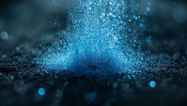 Fine blue particles cascading on reflective surface