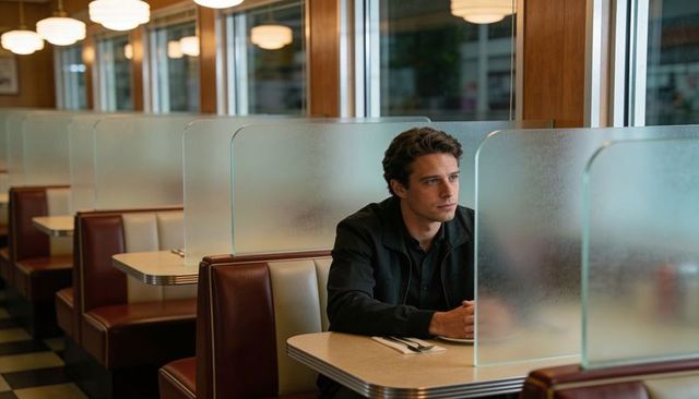 Man sitting alone in retro diner booth contemplating future with warm vintage lighting