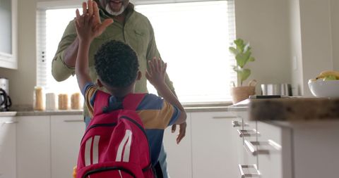 Grandfather high fiving grandson on school morning
