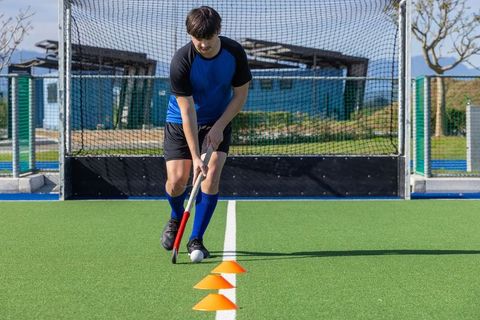 Field hockey athlete dribbling through cones during training