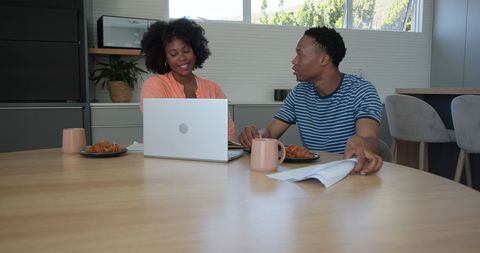Young Couple Collaborating at Home with Laptop and Documents