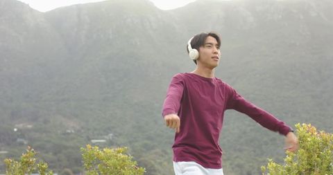 Asian Man Enjoying Music on Scenic Mountainside