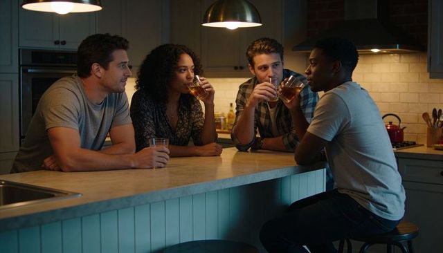 Friends sharing drinks and conversation around kitchen island during cozy evening hangout