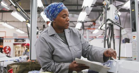 Skilled Female Mechanic Painting Car in Industrial Workshop