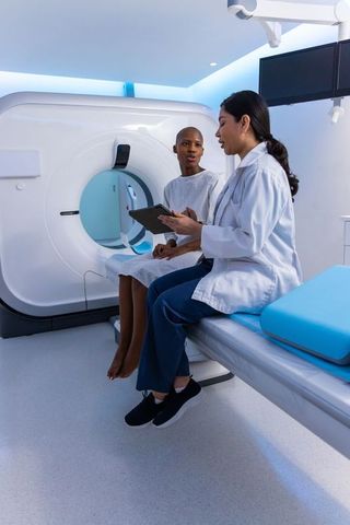 Clinician consulting black female patient before ct scan in modern radiology suite