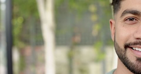 Smiling Man in Green Shirt Outdoors with Natural Backdrop