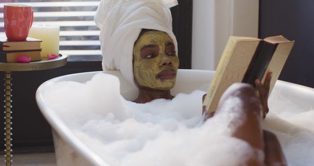 A woman with a facemask is relaxing in a bubble bath while reading a book. This serene and cozy scene embodies self-care and wellness routines. Perfect for articles on relaxation, self-love, home spa treatments, and promoting products related to beauty and wellness.