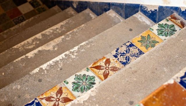 Worn Concrete Staircase with Colorful Floral Ceramic Risers Showing Patina and Texture