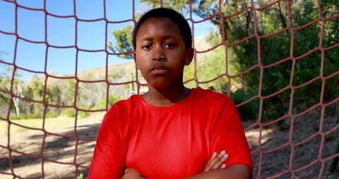 Confident Boy Standing Against Net in Outdoor Obstacle Course