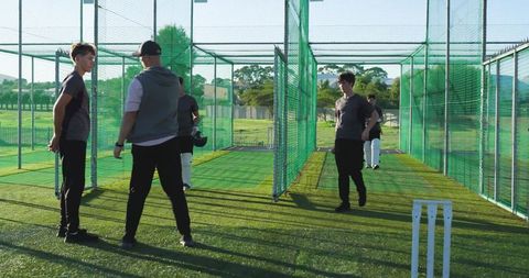 Youth cricket team practicing in outdoor nets with coach leading training and sportsmanship
