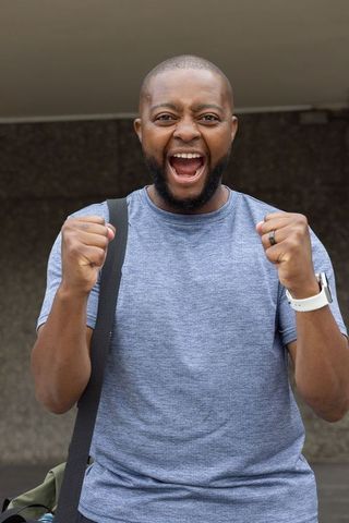 Triumphant african american man cheering with raised fists and wide smile for victory