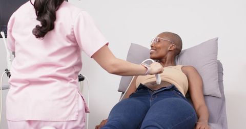 Female clinician performing abdominal ultrasound on smiling black woman wearing glasses