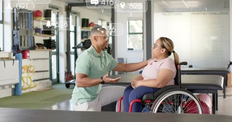 Kneeling therapist placing hand on woman in wheelchair during rehabilitation session