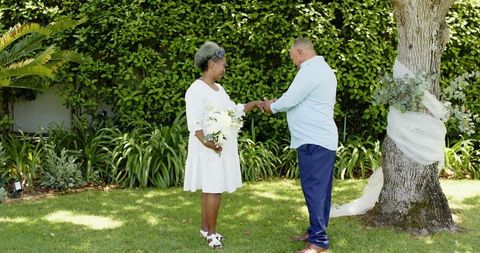 Senior Couple Exchanging Rings in Outdoor Garden Ceremony