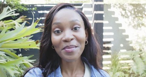 Portrait of plus person in a sunny courtyard with greenery and modern fence
