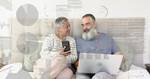 Mature couple collaborating on personal finance and analytics with laptop and smartphone