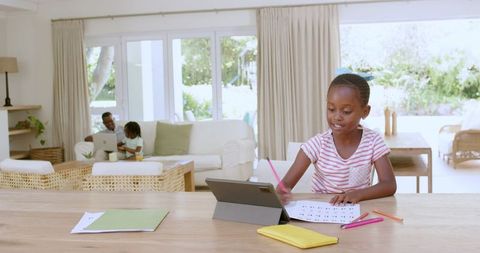 Girl Studying with Tablet at Home, Family in Relaxed Atmosphere