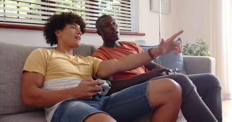 Two friends enthusiastically playing video games at home