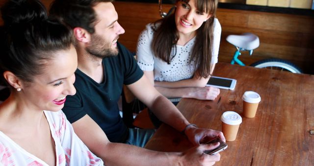 Friends Enjoying Coffee and Laughing at Cafe Table - Download Free Stock Images Pikwizard.com