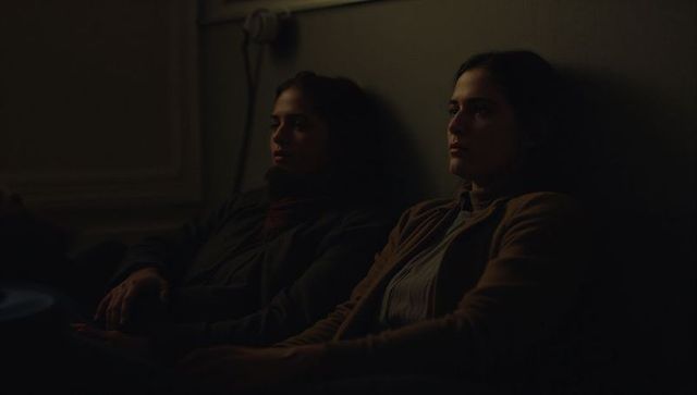Two women leaning back in dim minimalist lounge creating quiet introspective mood