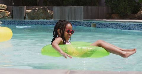 Joyful child relaxing in pool with inflatable ring on sunny day