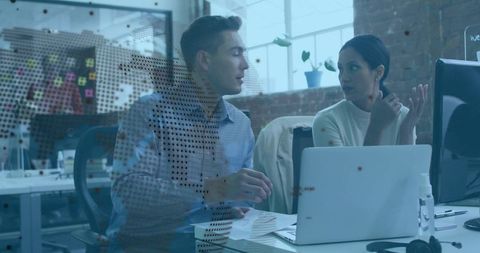 Coworkers collaborating and discussing project at laptop in modern open office with glass map