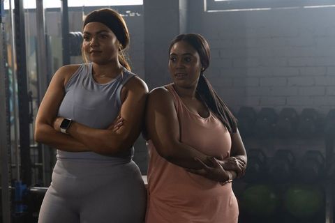 Confident african american fitness partners standing at weight rack resting between sets