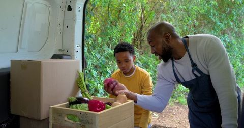 African american vendor teaching child about fresh farm vegetables from market van