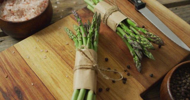 Image of two fresh asparagus bundles on wooden chopping board. fusion food, fresh vegetables and healthy eating concept.