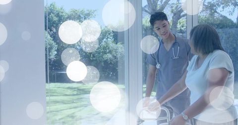 Caregiver helping senior woman with walker by sunlit garden patio