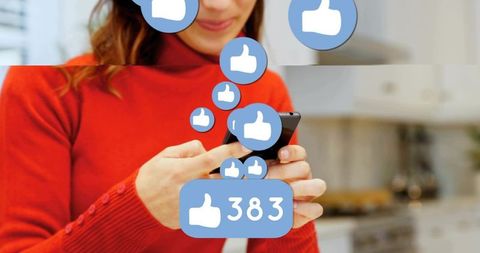 Woman receiving social media likes while using smartphone in home kitchen for engagement