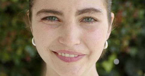 Smiling young woman making eye contact wearing silver hoop earrings closeup portrait