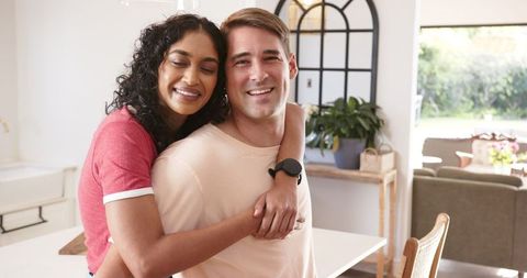 Smiling Diverse Couple Embracing in Modern Home Kitchen