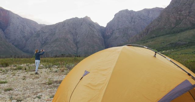 Woman Taking Photo of Mountain Landscape near Yellow Dome Tent - Download Free Stock Images Pikwizard.com