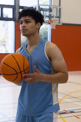 Athletic Young Man Holding Basketball on Indoor Gym Court